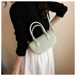 Detail of mint green ruched cylinder bag with vertical quilted texture and dual handles
