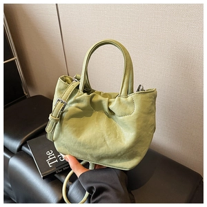 Detail of green pleated bucket bag showing soft texture and silver metallic buckle