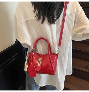 Red crocodile texture crossbody bag shown on a model against a minimalist staircase