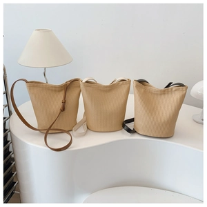 Drei beige gewebte Beuteltaschen mit braunen, weißen und schwarzen Lederriemen auf Display