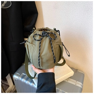 Detail of army green nylon drawstring bucket bag with mesh pockets and utility strap