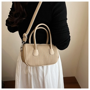 Detailed view of beige pleated pillow bag with vertical stitching on model