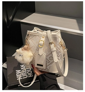 Detailed view of the creamy bucket bag featuring floral embossing and a plush sheep charm