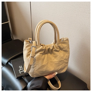 Close-up of beige cloud bag featuring pleated texture and adjustable strap detail