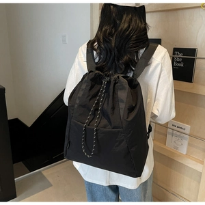 Detail view of durable woven shoulder straps and drawstring closure on black nylon backpack