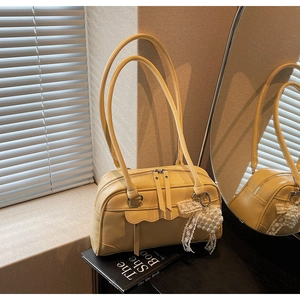 Detail of cream shoulder bag with scalloped flap and elegant pearl heart charm accessory