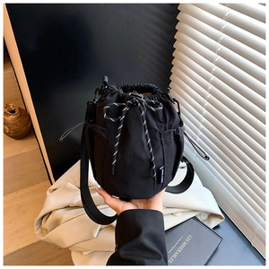 Detail of black drawstring bucket bag featuring a mesh side pocket and woven rope cord