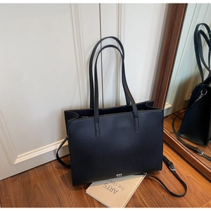 Detail of minimalist black pebbled leather tote bag with white logo and dual straps