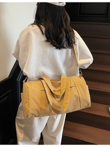 Large yellow canvas travel bag with adjustable strap shown on a model on stairs