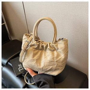 Detail view of beige ruched bucket bag with silver hardware and adjustable strap
