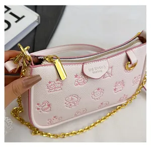 Détail du sac sous l'aisselle en cuir rose texturé avec gaufrage et chaîne dorée