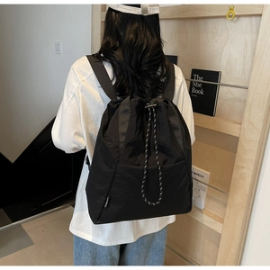 Rear view of black nylon drawstring backpack with FANDAIER tag on a casual model