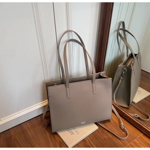 Detail view of taupe lychee leather tote bag with adjustable strap on wooden floor