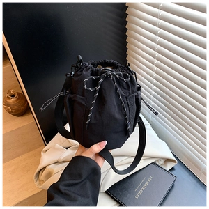 Close-up of black drawstring canvas bucket bag with mesh side pockets and nylon strap
