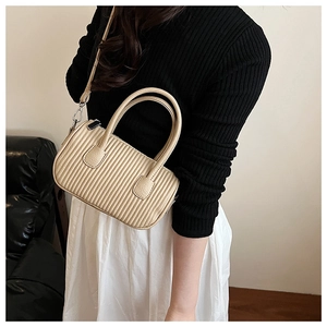 Detailed close-up of beige quilted mini pillow bag with vertical stripes and top handles