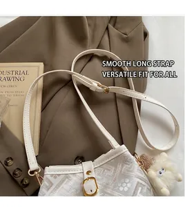 Detail of white embroidered shoulder bag with floral patterns and a plush doll charm