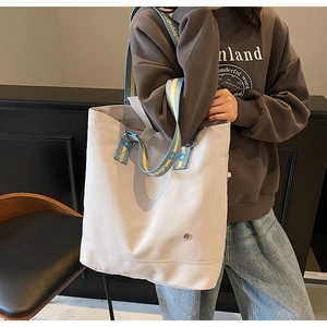 Detail of a large capacity canvas tote bag with a trendy yellow and blue lettered strap
