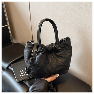 Detail of black pleated cloud bag with soft PU leather texture and thin shoulder strap