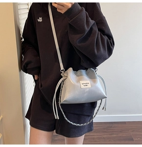 Detail view of light blue drawstring bucket bag with chain accent on oversized sweatshirt