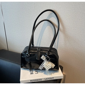 Detail of black PU leather underarm bag with elegant pearl heart pendant and silver zipper