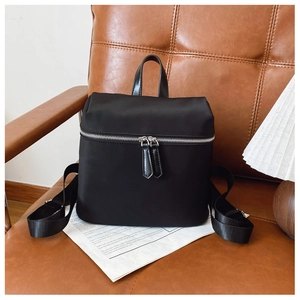 Detail shot of a black nylon backpack on a leather chair with retro lifestyle decor