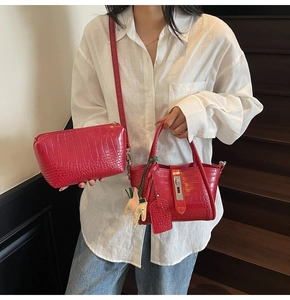Detailed view of red crocodile embossed leather handbag with metal lock and horse charm