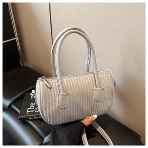 Detail of light gray barrel bag with wavy quilted texture and silver-tone hardware