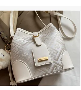 Detail view of cream bucket bag with geometric jacquard fabric and plush charm detail