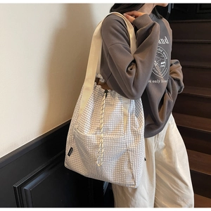 Detail shot of checkered drawstring bucket bag with textured fabric on a model