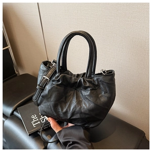 Detail shot of black ruched bucket bag with round handles and adjustable shoulder strap