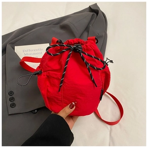 Detail of red drawstring bucket bag featuring a mesh side pocket and sporty cord knot