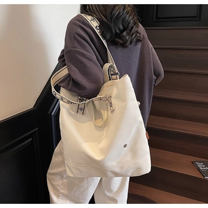Detail of off-white canvas tote bag featuring geometric print wide shoulder strap
