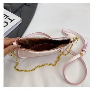 Vue détaillée d'un sac en cuir gaufré rose clair avec chaîne dorée et poche zippée intérieure