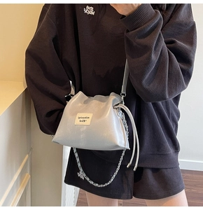 Detail of silver-grey bucket bag with drawstring closure and metal chain shoulder strap