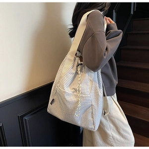 Detail of grey plaid drawstring bucket bag with FANGANER woven label and rope closure