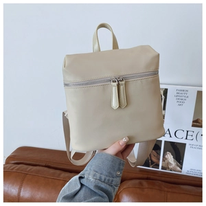 Detail view of cream backpack top handle and silver double zippers with long leather pulls