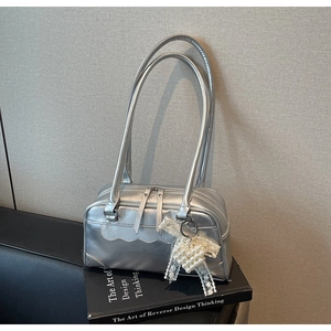 Close-up of metallic silver rectangular shoulder bag with pearl lace heart charm