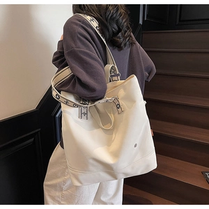 Detail view of large cream canvas tote bag with jacquard woven shoulder strap and metal buckle