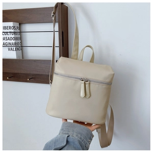 Close-up of minimalist beige nylon backpack with double zippers and front pocket detail