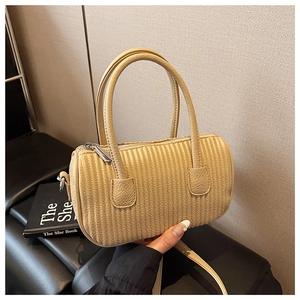 Detail of pleated beige cylinder bag showing reinforced handles and silver metal hardware
