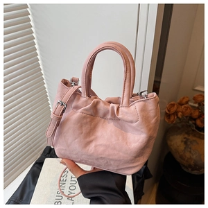 Detail of pink ruched bucket bag with silver hardware and textured leather finish
