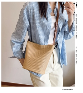 Detail of hand-woven straw bucket bag with adjustable dark brown leather shoulder strap