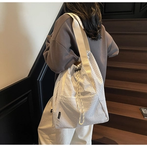 Detail showing the large capacity waffle textured bucket bag with decorative drawstrings