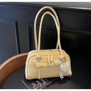 Detail of yellow shoulder bag with wavy pleats and pearl heart charm on a black background