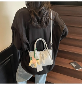 Detailed view of light gray crocodile pattern tote bag with stylish horse charm pendant