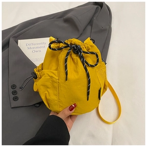 Detail of a yellow drawstring bucket bag made of soft nylon fabric with mesh side pocket