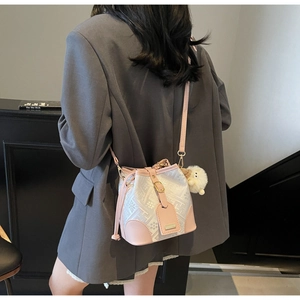 Detail showing bucket bag with jacquard texture, pink leather trim, and plush charm