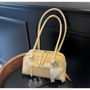 Close-up of yellow shoulder bag with pearl heart charm and wavy pocket details