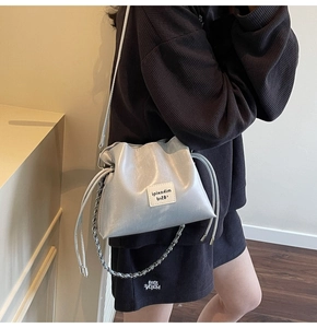 Detail view of silver drawstring bucket bag with metallic finish and chain strap