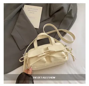 Détail du sac à main crème en cuir avec deux poches frontales et décoration nœud